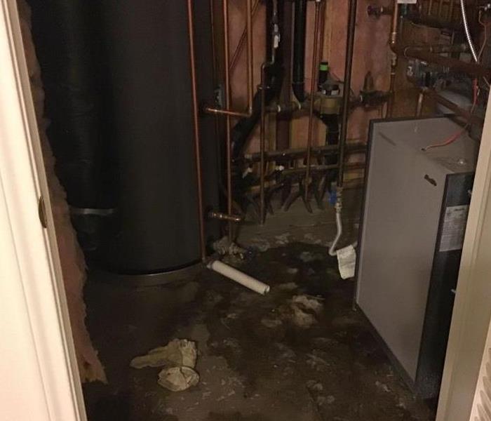 a room with a water heater and water on the floor