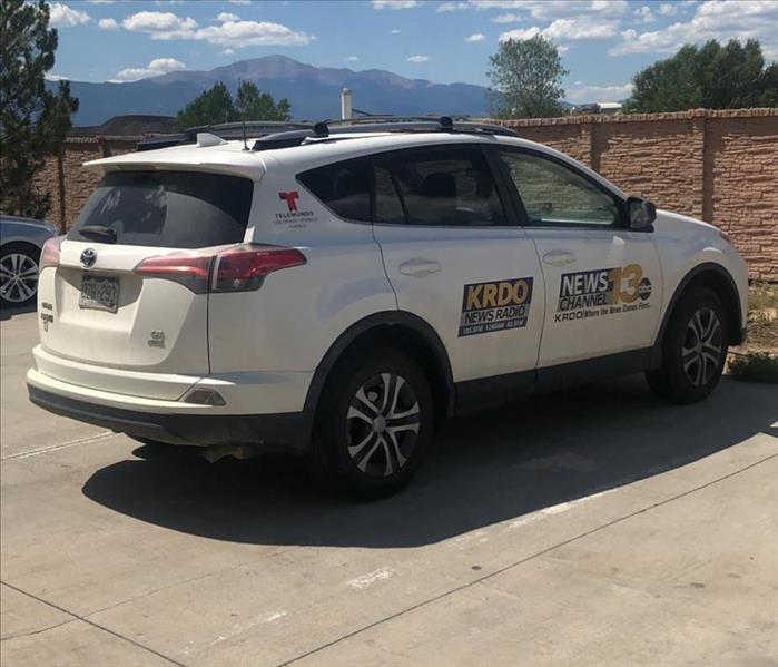 A vehicle with local news station information on it outside with mountains in the horizon.