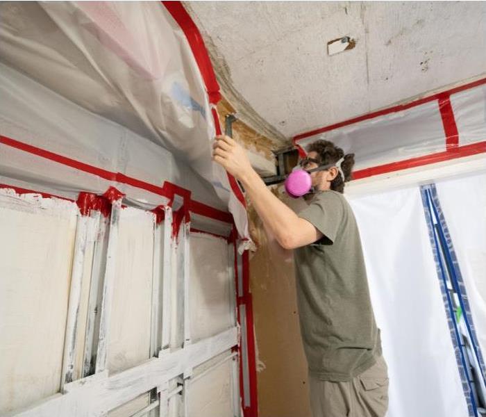 A man remediating the wall where there is mold.