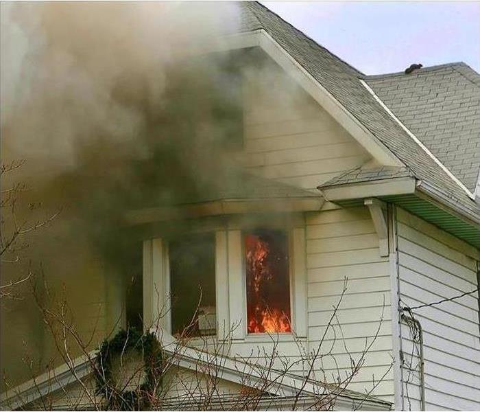 Image of flames coming out from a window in a residential home.