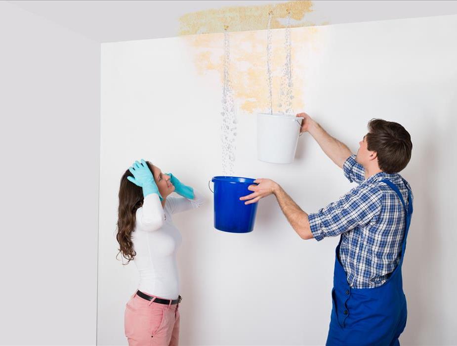 Image of 2 persons dealing with a leak from the ceiling of their house